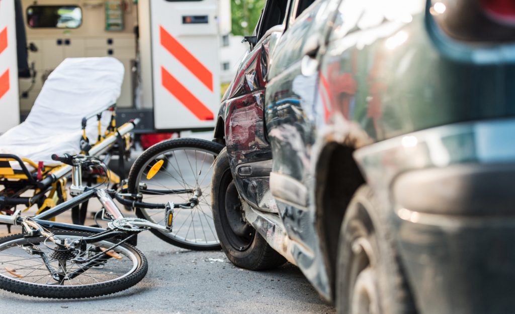 Bicycle accident scene with damaged car