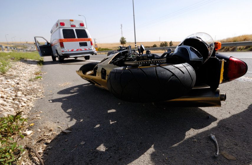 Fallen motorcycle on roadside with ambulance