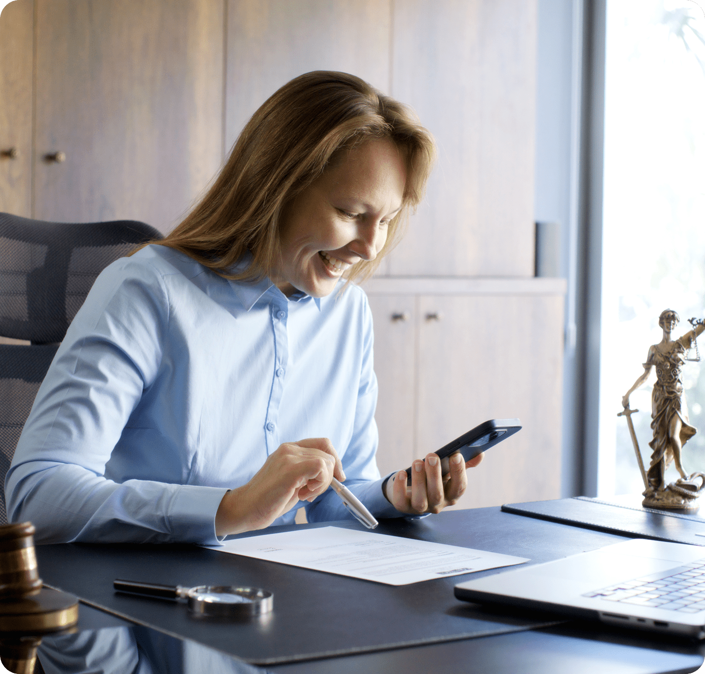 Smiling woman using smartphone at desk