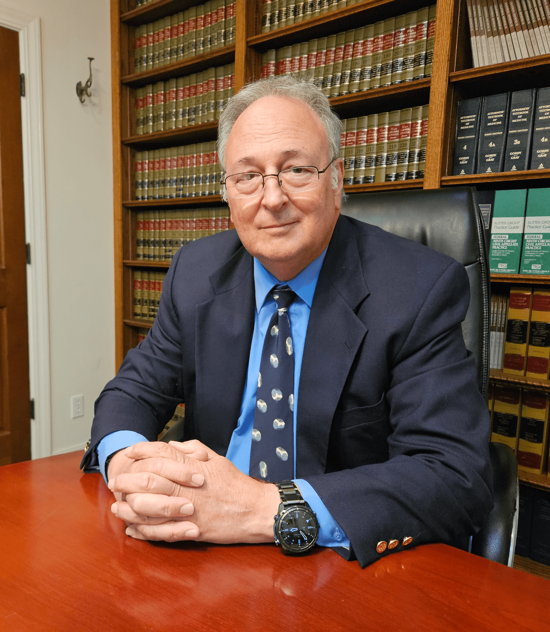 Man in suit seated at desk with lawbooks