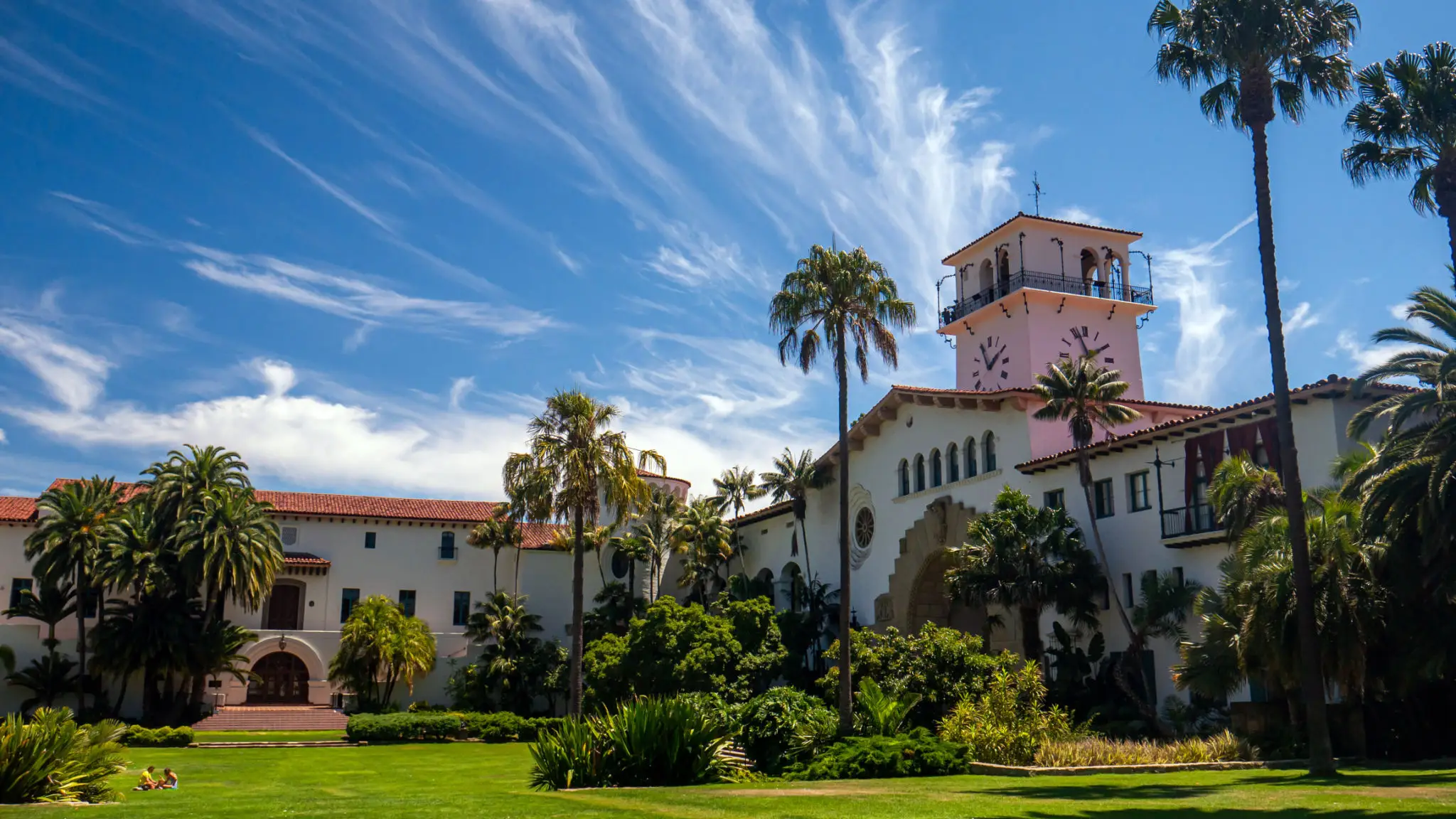 Spanish-style building with clock tower and palms