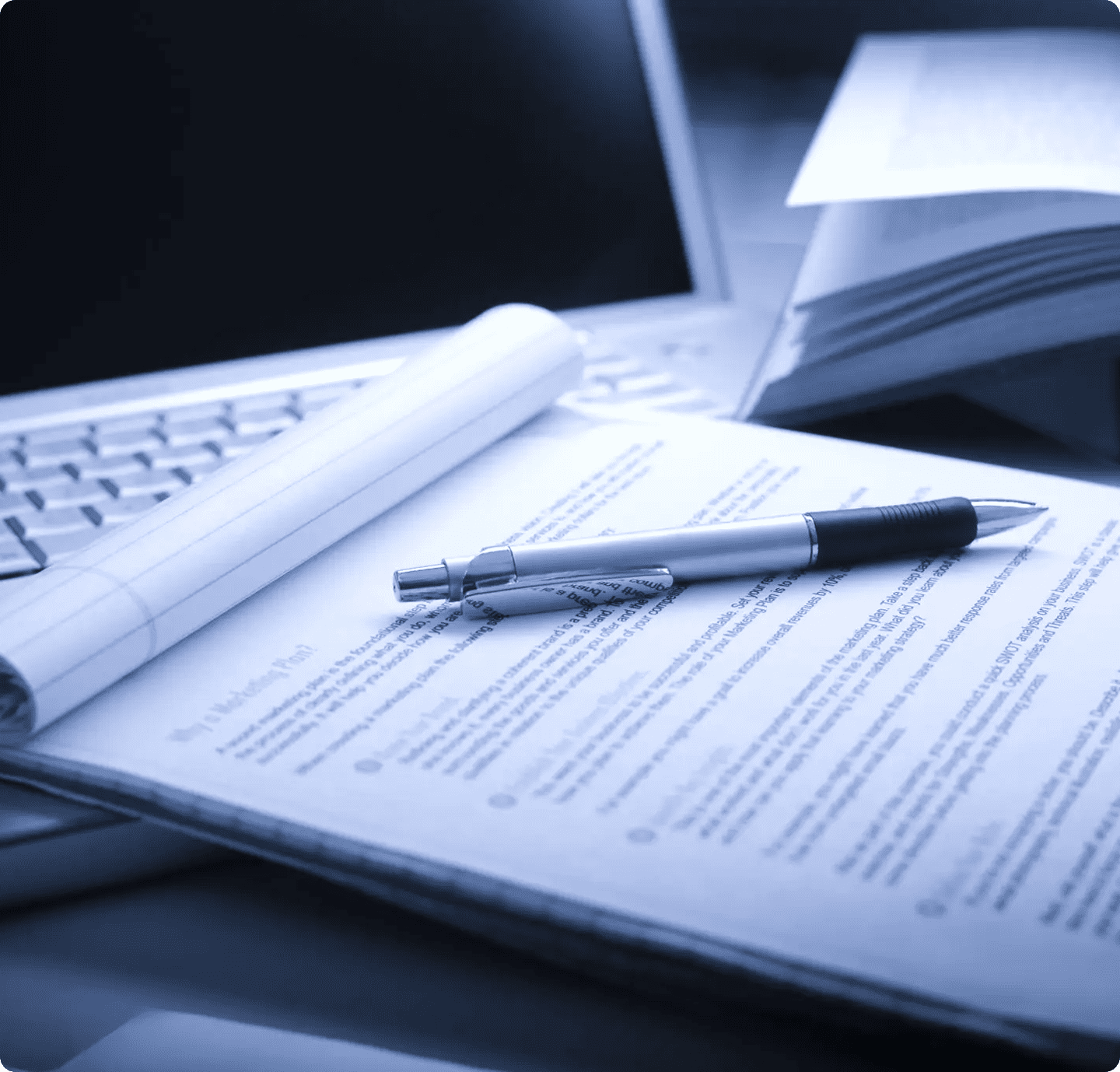 Pen on documents beside laptop keyboard