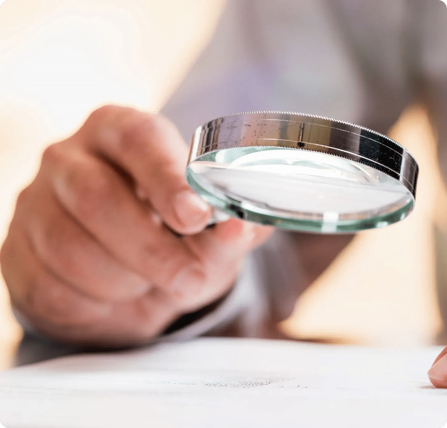 Hand holding magnifying glass over document