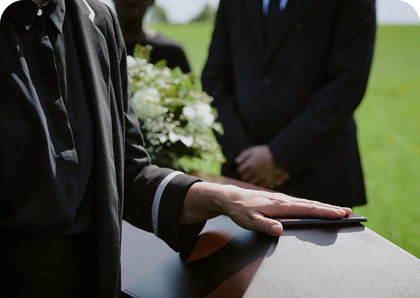 Person's hand on coffin at outdoor funeral